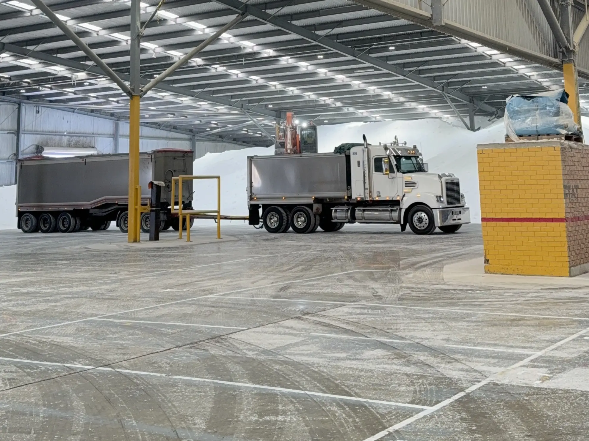 Two road trains loading under cover beside a fertiliser stockpile at the Lara storage shed