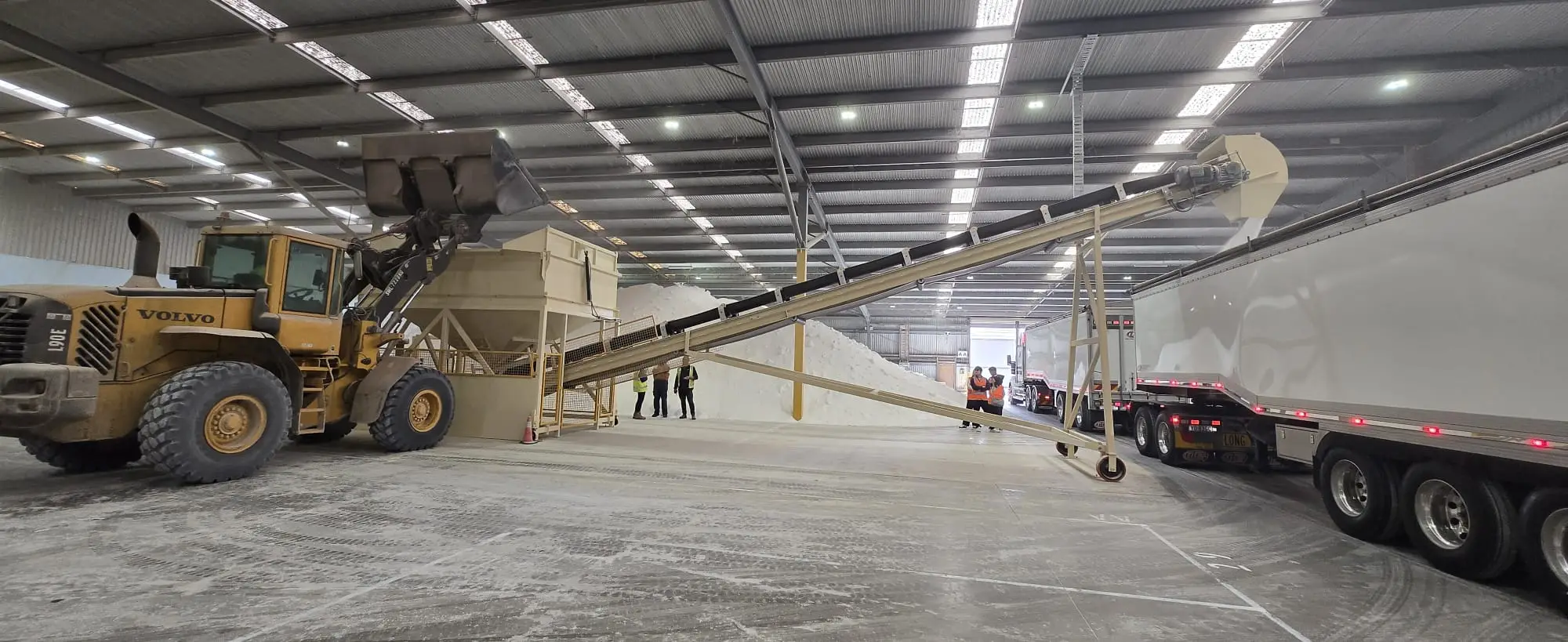 Front-end loader feeding a conveyor to load road trains inside the Lara storage shed